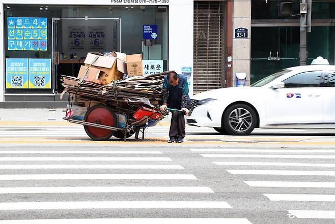 폐지가 가득 담긴 수레를 끌고 횡단보도를 건너고 있는 어르신. 동아일보DB