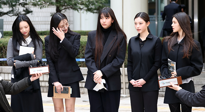 걸그룹 뉴진스(NJZ)가 지난 3월 서울 서초구 서울중앙지방법원에서 열린 ‘기획사 지위보전 및 광고계약 체결 등 금지’ 가처분 신청의 심문기일을 마친 뒤 법원 청사를 나서며 취재진 질문에 답하고 있다. 왼쪽부터 하니, 민지, 혜인, 해린, 다니엘. [연합]