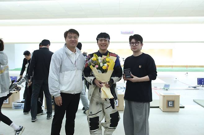 마지막 경기를 마치고 이현태 코치(왼쪽)와 박하준 선수(오른쪽)가 준비한 축하 꽃다발을 받은 KT 김상도. KT 사격단 제공