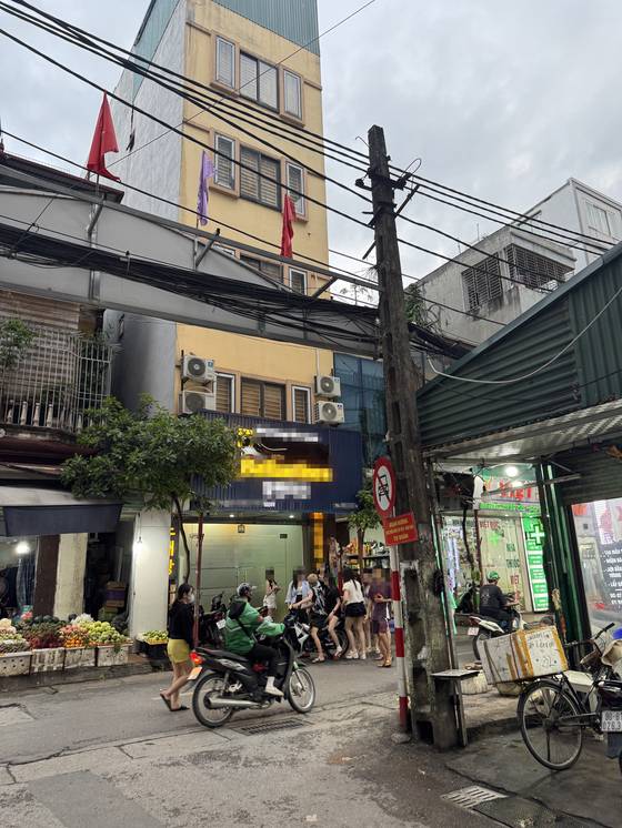 On June 27, women get off a motorcycle outside a massage parlor in Hanoi. Two more motorcycles carrying young women arrive shortly after three Korean men enter the building. [NAM JI, WOMEN MIGRANTS HUMAN RIGHTS CENTER OF KOREA]