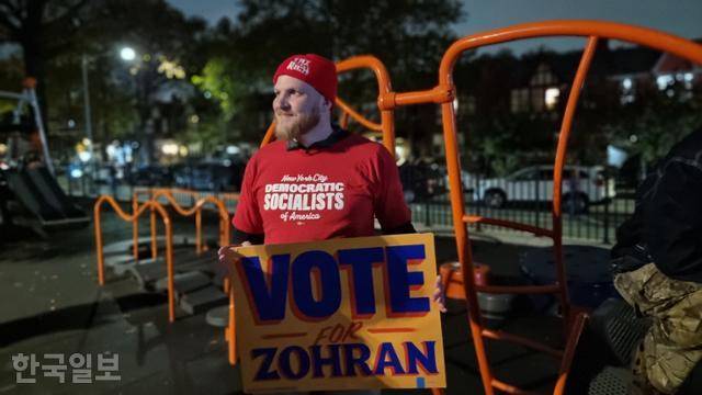 조란 맘다니 미국 민주당 뉴욕시장 후보의 지지자인 알렉산더 패터슨이 3일 뉴욕 퀸스 롱아일랜드시티 놀이터에서 본보와 인터뷰한 뒤 손팻말을 들어 보이고 있다. 뉴욕=권경성 특파원