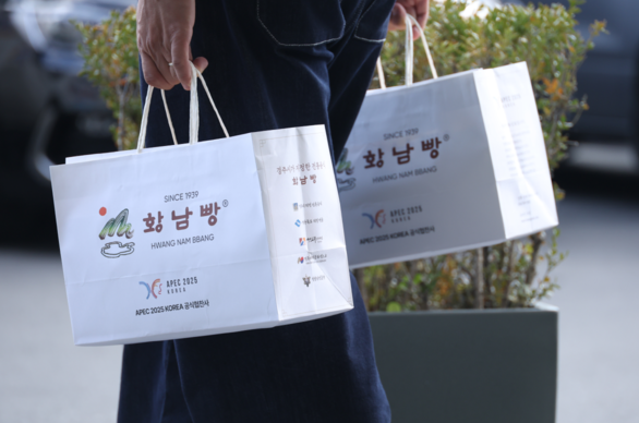 경주 아시아태평양경제협력체(APEC) 정상회의 공식 협찬사인 황남빵 본점에서 시민들이 구매한 황남빵을 들고 이동하고 있다. 연합뉴스