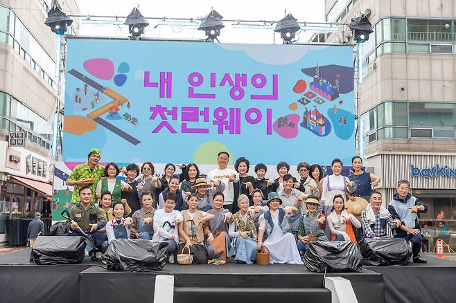 '내 인생의 첫런웨이' 현수막이 걸린 무대에서 시니어 모델 프로그램 참가자들이 기념촬영을 하고 있다. ⓒ칠곡군 제공