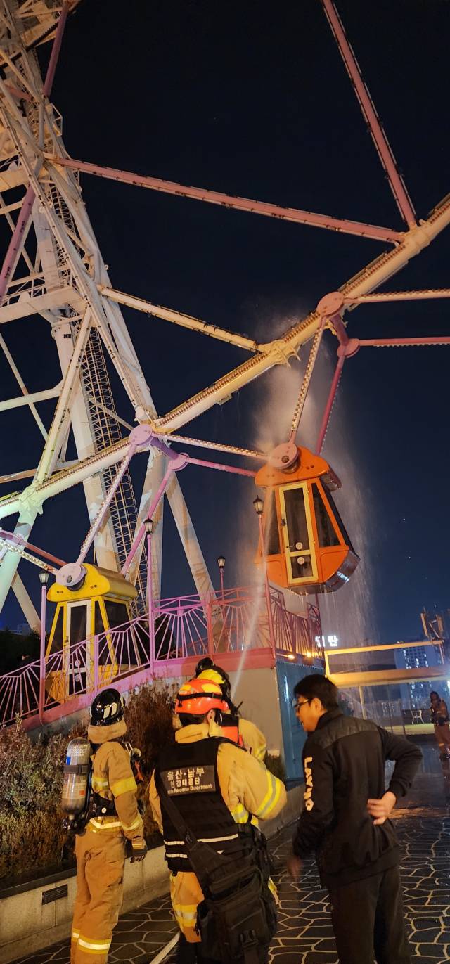 5일 밤 울산 남구 롯데백화점 관람차에서 화재가 발생하자, 출동한 소방대원들이 탑승칸을 향해 물을 뿌리며 진화 작업을 벌이고 있다. 울산소방본부 제공