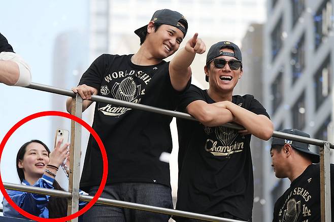 LA다저스의 간판 스타 오타니 쇼헤이가 3일(현지 시간) 메이저리그 우승 기념 퍼레이드에 참석해 기뻐하고 있다. 그의 왼쪽에서 구형 아이폰으로 사진을 찍고 있는 여성이 그의 아내 다나카 마미코다. AP=뉴시스