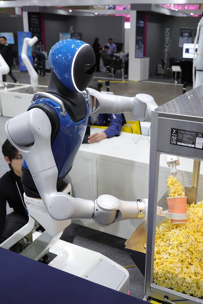 휴머노이드 “주문하신 팝콘 나왔습니다” 5일 경기 고양시 킨텍스에서 열린 ‘2025 로보월드’에서 휴머노이드가 관람객의 주문을 받아 팝콘을 담고 있다. 정부나 기업들은 로봇·자율주행차·생산라인 등에서 역할이 크게 확대될 것으로 예상되는 피지컬 AI에 투자를 늘릴 예정이다. 연합뉴스