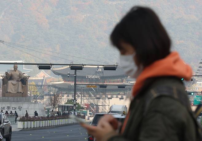 A person wearing a mask walks through Gwanghwamun Square in central Seoul on Friday. (Yonhap)