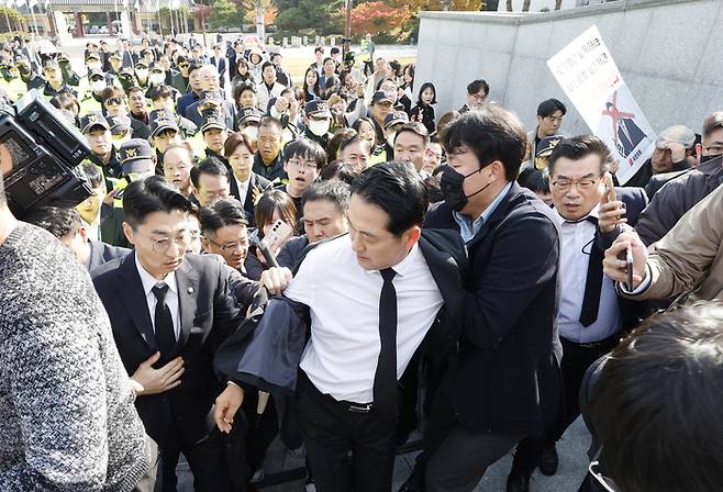 장동혁 국민의힘 대표(가운데)가 6일 광주 국립5·18민주묘지를 참배하기 위해 경내에 들어서자 일부 인사들이 장 대표의 양복을 잡아당기며 몸으로 막는 사태가 벌어졌다. 이날 장 대표 양복 상의의 단추가 떨어졌다. [사진 출처 = 뉴스1]