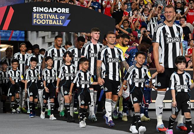 뉴캐슬 유나이티드 선수들이 지난 7월 싱가포르 국립경기장에서 열린 아스널과의 프리시즌 친선경기 시작 전 어린이 마스코트들과 함께 입장하고 있다. 로이터