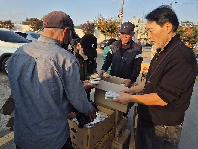 주훈 포항참사랑교회 목사(오른쪽)와 자원봉사자들이 지난 5일 포항시 북구 대흥동의 한 공터에서 어르신들에게 음식을 나눠주고 있다.