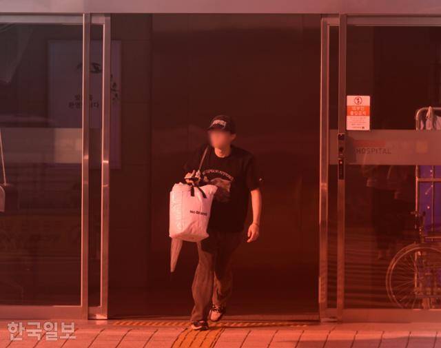 9월 서울 시내에 위치한 한 임상시험센터에서 수일간의 병동 합숙을 마친 참여자들이 짐을 들고 건물 밖으로 나오고 있다. 붉은 아크릴판을 투과해서 촬영. 최주연 기자