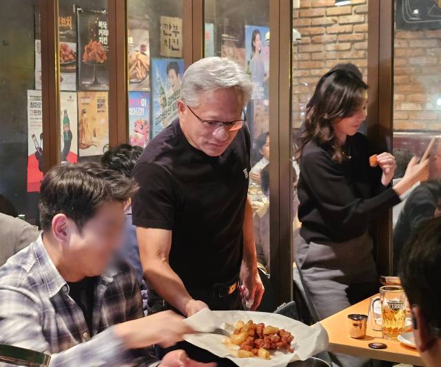 젠슨 황 엔비디아 최고경영자가 지난달 30일 서울 삼성동 한 치킨집에서 이재용 삼성전자 회장, 정의선 현대차그룹 회장과 치맥 회동을 하던 중 다른 손님들에게 치킨을 나눠주고 있다. 연합뉴스