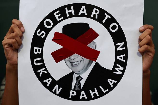 인도네시아 정부가 수하르토 전 대통령에게 국가 영웅 칭호를 부여한 10일 자카르타에서 이를 반대하는 시위에 참가한 이가 “수하르토는 영웅이 아니다”라는 손팻말을 들고 있다. 로이터 연합뉴스