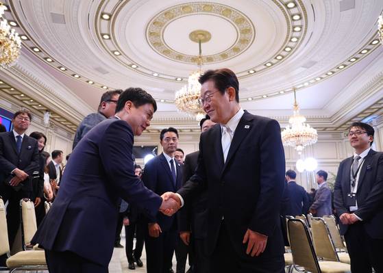 President Lee Jae Myung, right, shakes hands with correspondents after ending his press conference held at the Blue House’s Yeongbingwan state guest house in central Seoul in September. [YONHAP]