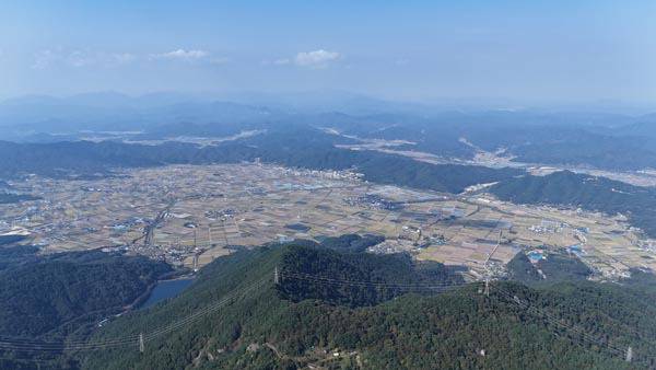 합천 운석 충돌구 환 종주 세 번째 구간인 송림재~미타산~큰고개 에서 미타산 정상에 서면 조망이 활짝 열린다. 취재팀이 전망 덱인 ‘별쿵’ 포토존에서 드론을 날려 찍은 운석 충돌구 모습이다. 멀리 북쪽으로 합천의 산인 오도산과 두무산·가야산이 펼쳐지며 그릇 모양을 한 초계면과 적중면 분지를 두른 맞은편 능선에 두 번째 구간 때 걸었던 단봉산과 옥두봉이 보인다.