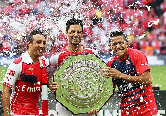 2014 FA 커뮤니티 실드에서 우승한 후 산티 카솔라(왼쪽)가 우승 트로피를 든 미켈 아르테타와 알렉시스 산체스와 기쁜 표정을 짓고 있다. Getty Images코리아