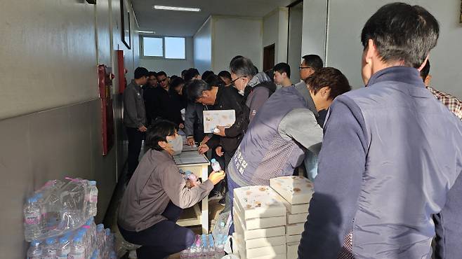 13일 오전 광주 광산구 금호타이어 광주공장에서 '광주공장 가동 조합원 설명회'가 열렸다. 사진은 설명회가 열린 회의장에 들어가기 전 근로자들이 명부를 작성하고 선물과 생수 등을 받고 있는 모습. /박준호 기자 bjh@namdonews.com