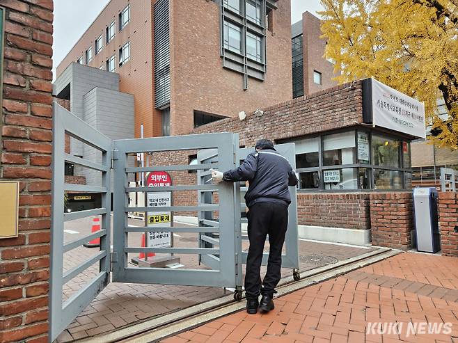 13일 오전 8시13분 이화여고 시험장 출입문 통제를 하던 경비원이 문을 반쯤 폐쇄하고 있는 모습. 서지영 기자&nbsp;