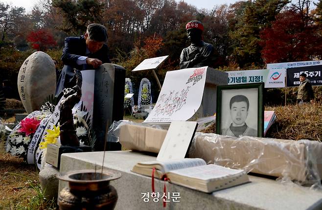 전태일 열사 55주기인 13일 경기도 남양주시 모란공원묘원에서 열린 추모식에서 열사의 동생 전태삼 씨가 민주노총의 포스터를 추모비에 붙이고 있다. 김창길 기자