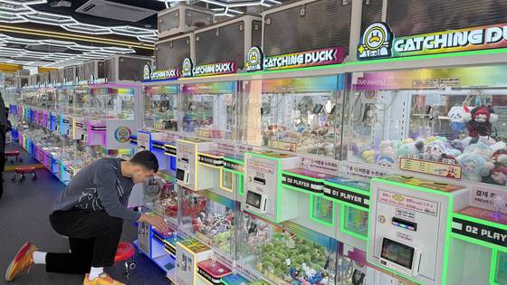 A person plays a claw machine at Catching Duck in Hongdae on Nov. 9. [WOO JI-WON]