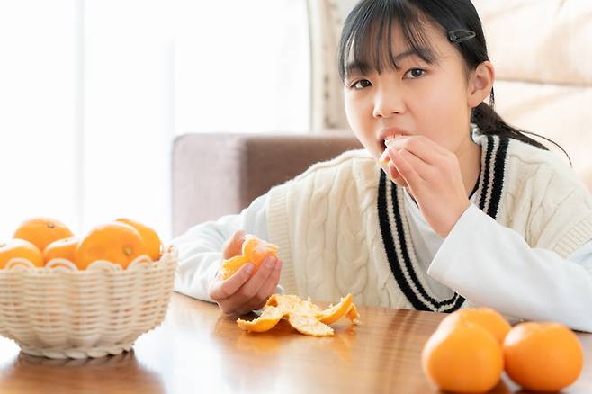 오렌지 껍질을 벗겨 먹고 있다. 겨울철에는 비타민C를 잘 챙겨 먹어야 한다. 비타민C는 감기 예방과 면역력 강화, 피부 건강 유지, 상처 회복 촉진에 도움이 된다. 귤도 하루에 2~3개만 먹으면 성인의 비타민C 하루 권장 섭취량을 충족할 수 있다. 사진=게티이미지뱅크