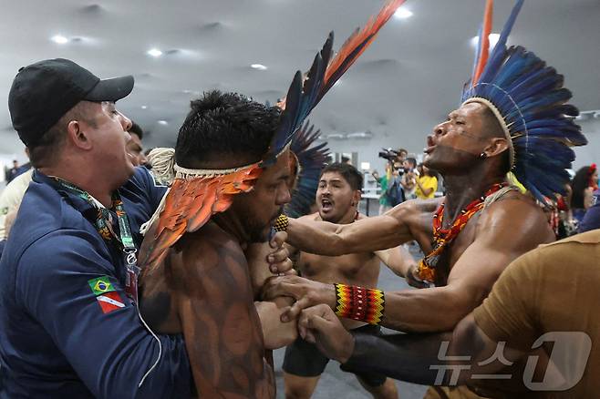 An Indigenous demonstrator is held by a staff member as protesters force their way into the venue hosting the UN Climate Change Conference (COP30), in Belem, Brazil, November 11, 2025. REUTERS/Anderson Coelho TPX IMAGES OF THE DAY ⓒ 로이터=뉴스1