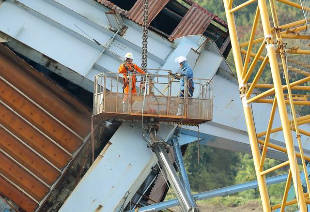 지난 12일 오후 울산화력발전소 보일러타워(5호기)에서 추가 붕괴를 막기 위해 작업자들이 고가 사다리차를 타고 크레인으로 상부 구조물을 고정하는 작업을 진행하고 있다.