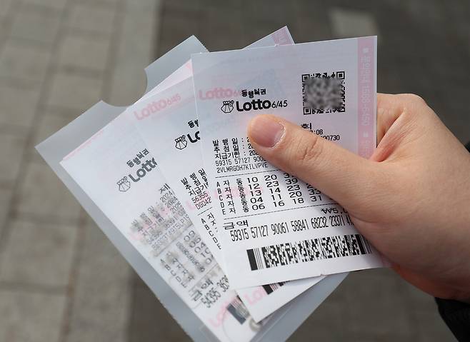 A person holds their lottery ticket in front of a lottery shop in Nowon District, northern Seoul, on Jan. 1, 2024. [YONHAP]