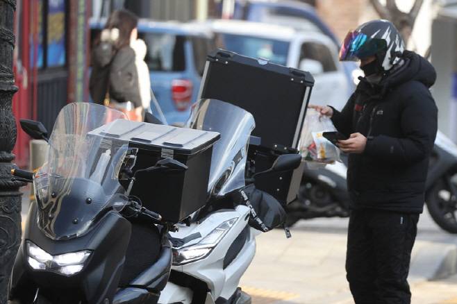 이강일 더불어민주당 의원이 대표 발의한 ‘생활물류서비스산업발전법 일부개정법률안’이 국회 본회의를 통과했다. 사진은 한 배달원이 주문 음식을 오토바이에 싣고 있는 모습. (연합뉴스)