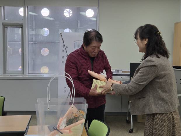 '시니어 시인학교' 수강생 김용규씨가 최소희 작가에게 꽃다발과 시집을 건네받으며 웃음짓고 있다. 사진=우예주 기자