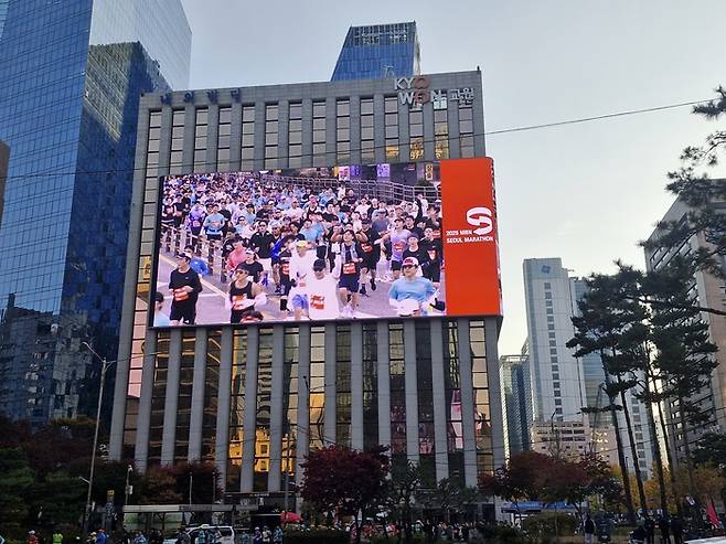 16일 2025 MBN서울마라톤 참가자들이 도심을 질주하는 모습이 을지로 교원빌딩에 설치된 매경 옥외전광판 M시티 스크린에 생중계 되고 있다. [이승환 기자]