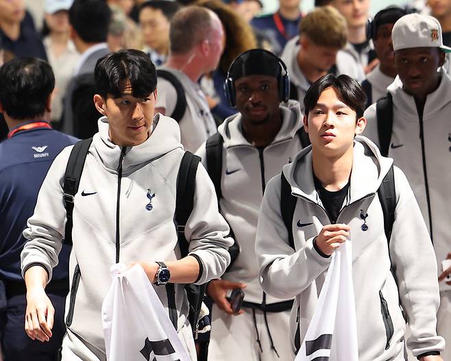 손흥민(좌)-양민혁이 태극기를 들고 인천국제공항으로 들어서고 있다