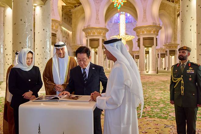 이재명 대통령과 김혜경 여사가 17일(현지 시각) 아랍에미리트 아부다비의 셰이크 자이드 그랜드 모스크를 방문해 책자를 살펴보고 있다./뉴시스