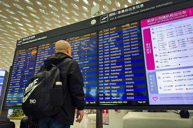 한 중국인 여행객이 선전 바오안 국제공항에서 국내선 및 국제선 항공편 일정과 체크인 카운터 배치를 표시하는 게시판을 보고 있다.[게티이미지]