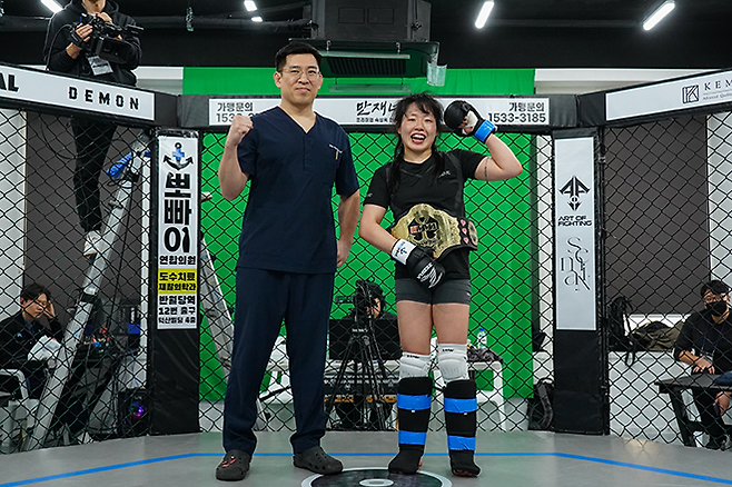 포토: 초대 KMMA 여성부 슈퍼스트로급 챔피언으로 등극한 오정은(오른쪽)에게 KMMA에이전시 대표이사 대구 뽀빠이연합의원 김성배 대표원장이 시상하고 있다. 사진=스탠다드앤드프로그레스 스포츠에이전시 제공