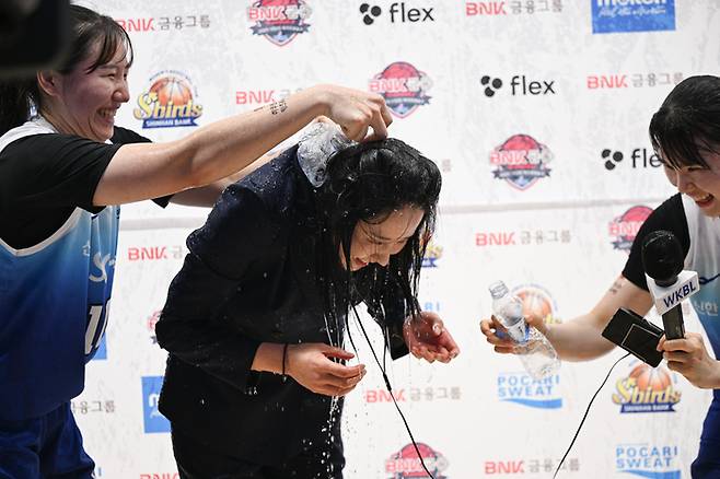신한은행 최윤아 감독이 21일 인천 도원체육관에서 열린 BNK금융 2025~2026 여자프로농구 정규리그 하나은행전 승리로 데뷔 첫 승을 따낸 후 선수들의 물세례를 받고 있다. 사진 | WKBL