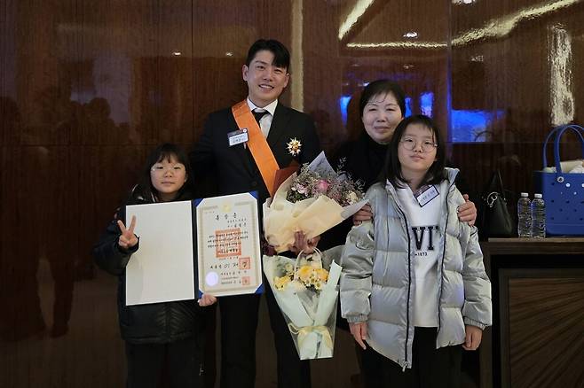 한국 정구의 간판 김범준(문경시청)이 21일 체육훈장 청룡장을 받은 뒤 어머니, 두 딸과 기쁨을 나누고 있다. 김범준 제공