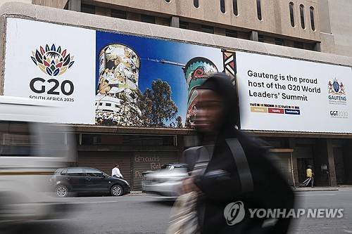 20일(현지시간) 요하네스버그 시내의 G20 광고판 앞을 지나가는 여성 [UPI 연합뉴스 자료사진 재판매 및 DB 금지]