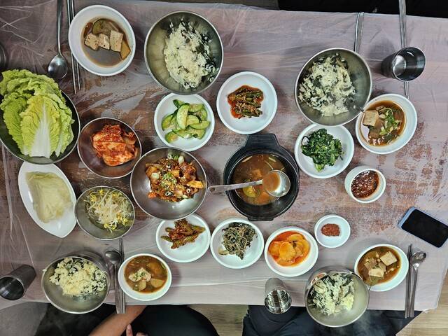 석포면 로컬 맛집 '뜰가든'에서 제공되는 곤드레밥 한 상. 곤드레밥을 중심으로 된장찌개, 김치, 나물류, 오이무침, 고추장아찌, 제육볶음 등이 정갈하게 차려져 전통 한식의 소박하고 풍성한 맛을 보여주는 식탁 풍경. 석포면 제공