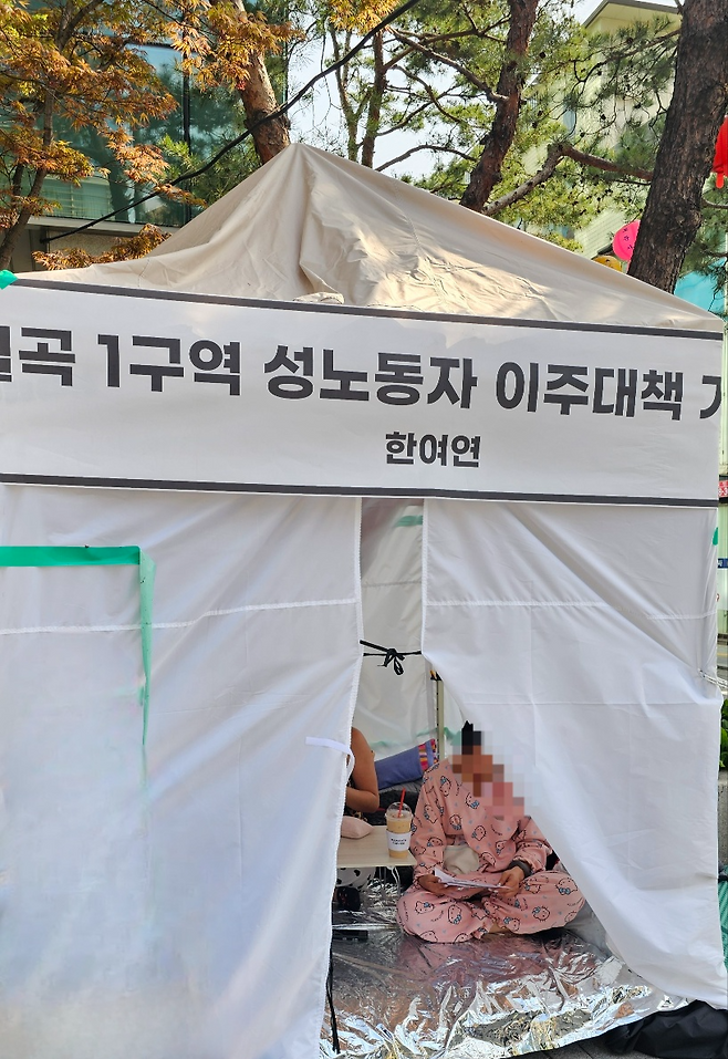 A sex worker from one of the brothels at Miari Texas, Kim, sits inside a tent set up in front of the Seongbuk-gu Office on April 21. (Choi Jae-hee/The Korea Herald)