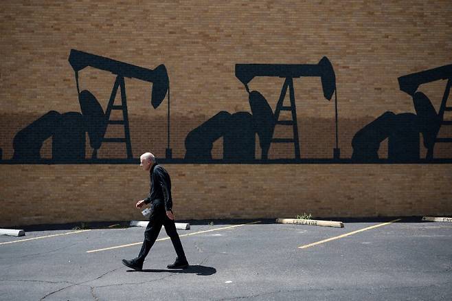 미국 독립 에너지 업체 다이아몬드백 에너지의 한 고위 엔지니어가 6월 11일(현지시간) 텍사스주 미들랜드의 '펌프 잭(채유기)' 벽화 앞을 지나고 있다. JP모건은 24일 공급 감축이 없다면 2027년 말에는 국제 유가가 배럴당 30달러 시대에 진입할 것이라고 전망했다. 로이터 연합