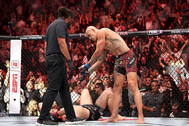 ‘이것 좀 보라고’. 패한 뒤 누워 있는 마고메드를 양손으로 가리키는 ‘밈 동작’을 선보이고 있는 페레이라 [게티이미지]