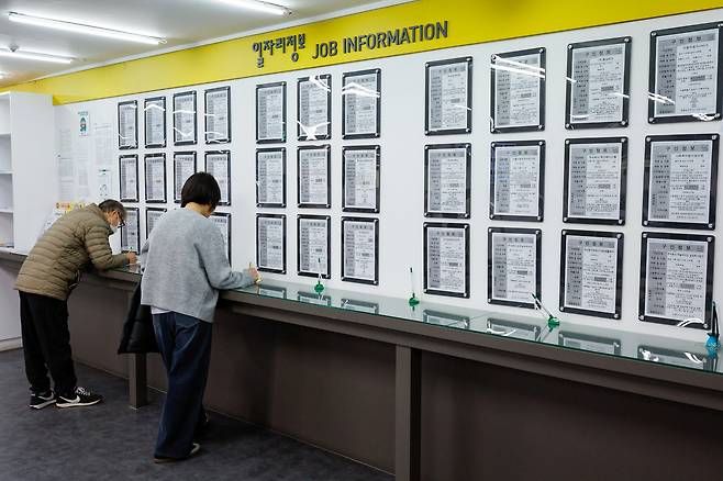 People fill out forms in front of a job information board at the Seoul Western Employment and Welfare Plus Center in Mapo District, western Seoul, on Nov. 12. [NEWS1]