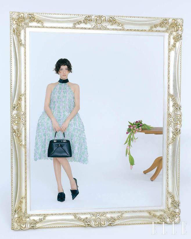 지수가 입은 구조적 형태가 인상적인 엠브로이더리 스캘럽 드레스, 블랙 카프스킨 스몰 디올 시갈 백, 슈즈는 모두 Dior.