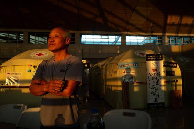 조병호(67)씨가 22일 아침 전남 무안국제공항 유가족 쉘터에서 붉게 물드는 여명을 바라보고 있다. 지난 참사로 각별했던 형을 잃은 그는 "처음보다 지금이 오히려 더 힘들다"며 "시간이 지날수록 불쑥불쑥 올라오는 슬픔의 크기가 커진다"고 털어놨다. 무안=하상윤 기자