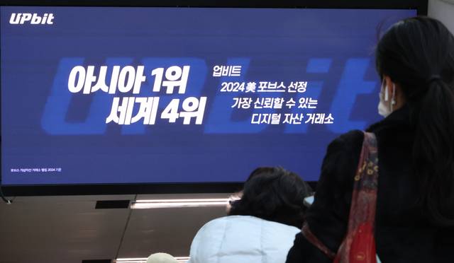 지난 11월 28일 서울 한 지하철역에 설치된 업비트 광고 앞을 시민들이 지나가고 있다. 연합뉴스