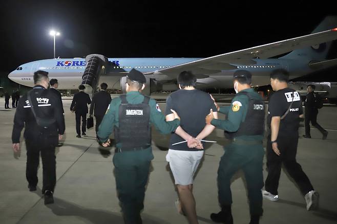 Korean police escort Korean detainees to a plane at Techo International Airport, in Phnom Penh, Cambodia on Oct. 18.  [EPA/YONHAP]