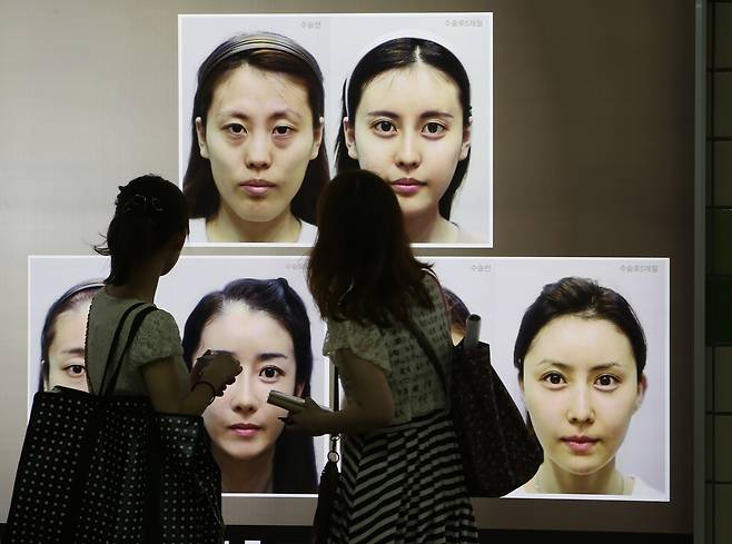 Commuters view cosmetic surgery advertisements in a Seoul subway station on July 26, 2012. [JOONGANG ILBO]