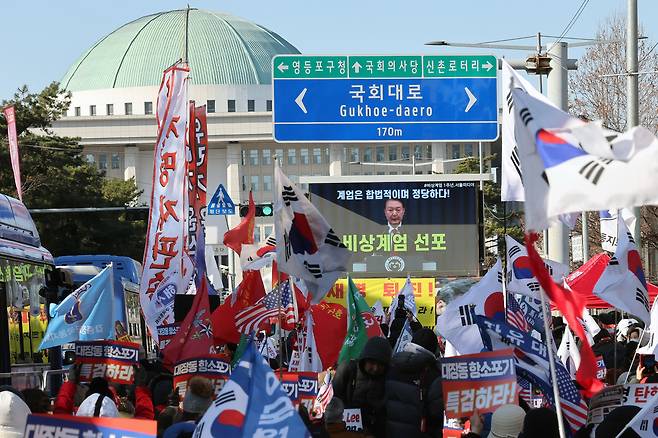 Conservative civic groups hold a rally outside the National Assembly in western Seoul on Dec. 3 while watching a video of former President Yoon Suk Yeol declaring martial law on Dec. 3, 2024. [NEWS1]