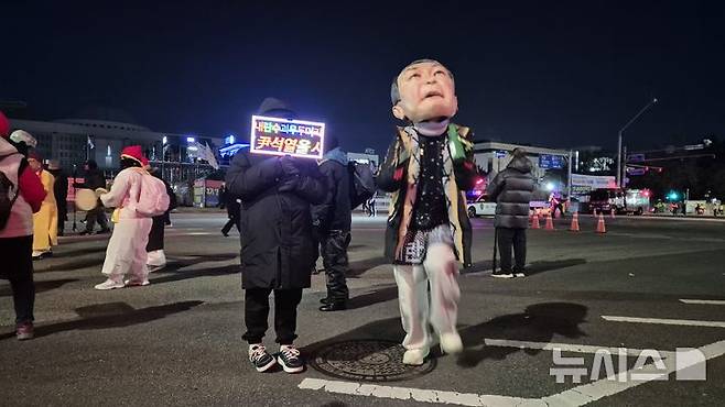 [서울=뉴시스] 전상우 수습기자 = 3일 오후 서울 여의도 국회의사당 인근에서 열린 '내란청산·사회대개혁 시민대행진'에서 한 참가자가 윤석열 전 대통령을 풍자한 대형 탈을 쓰고 춤을 추고 있다. 옆 참가자는 '내란수괴 윤석열을 심판하라'는 LED 피켓을 들고 있다. 2025.12.03. swoo@newsis.com